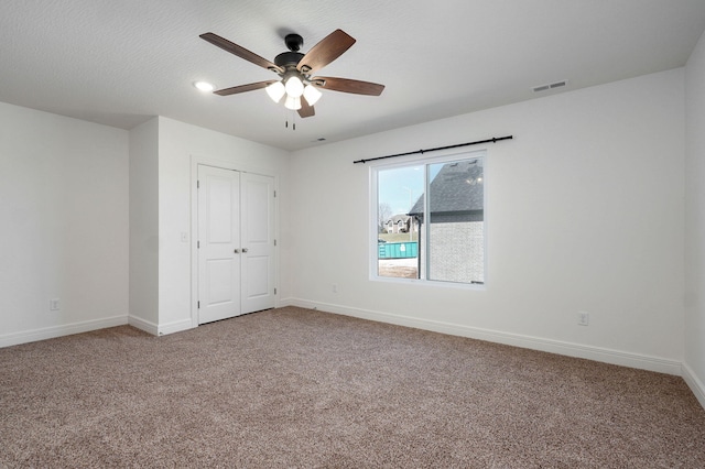 unfurnished bedroom featuring a closet, light colored carpet, visible vents, a ceiling fan, and baseboards