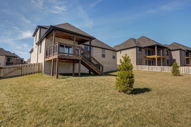 back of property with ceiling fan, a fenced backyard, brick siding, stairs, and a yard