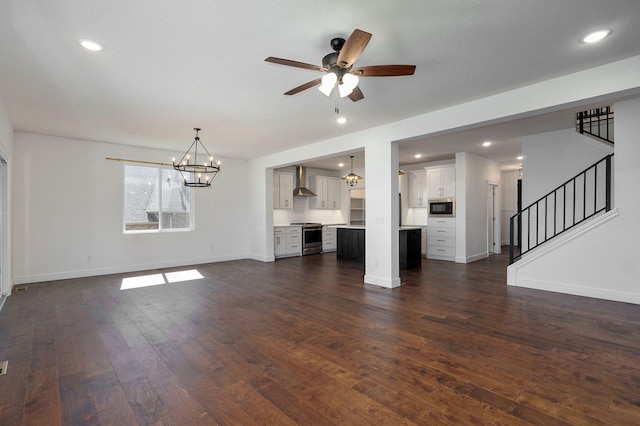 unfurnished living room with baseboards, dark wood finished floors, stairs, ceiling fan with notable chandelier, and recessed lighting