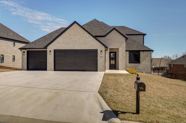 french country home featuring a garage, driveway, brick siding, and a front lawn