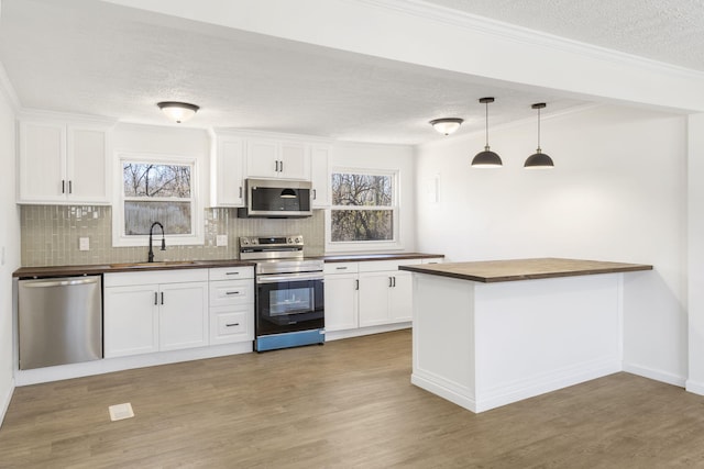 kitchen featuring a sink, appliances with stainless steel finishes, light wood-type flooring, and butcher block counters