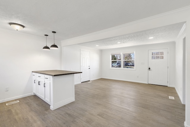 kitchen featuring visible vents, crown molding, a textured ceiling, and wood finished floors