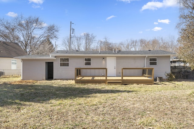 rear view of house featuring central AC unit, fence, a deck, and a lawn