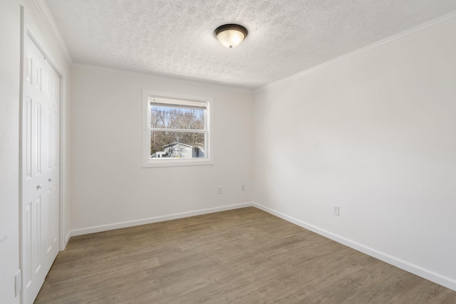 unfurnished bedroom featuring a closet, a textured ceiling, baseboards, and wood finished floors