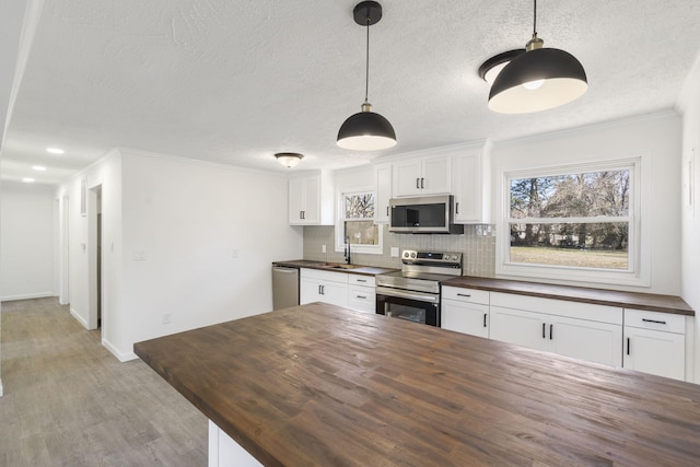 kitchen with butcher block counters, backsplash, appliances with stainless steel finishes, light wood-style floors, and a sink