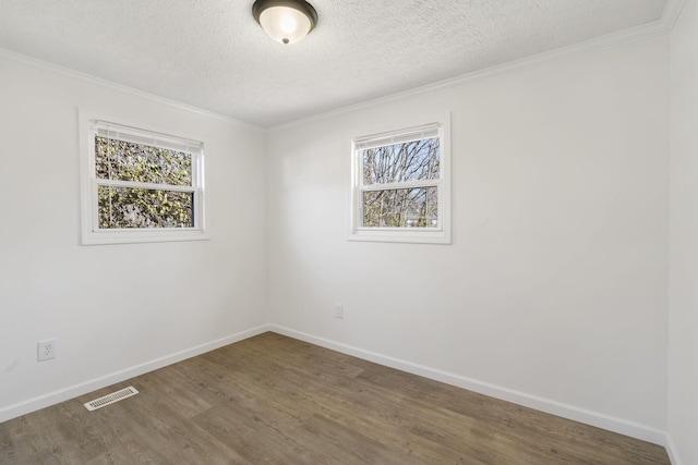 spare room with baseboards, visible vents, wood finished floors, crown molding, and a textured ceiling