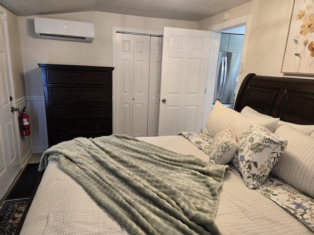 bedroom featuring a wainscoted wall, an AC wall unit, a closet, and freestanding refrigerator