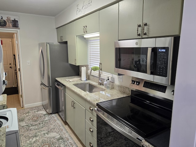 kitchen featuring baseboards, light stone counters, ornamental molding, stainless steel appliances, and a sink