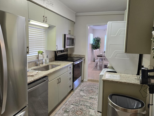 kitchen featuring stainless steel appliances, stacked washer / dryer, light tile patterned flooring, and a sink