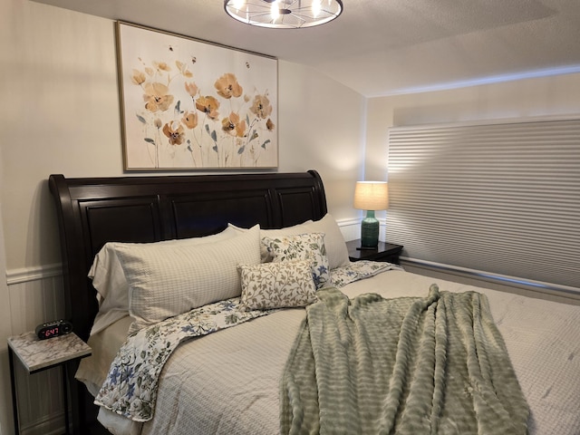 bedroom featuring vaulted ceiling and wainscoting