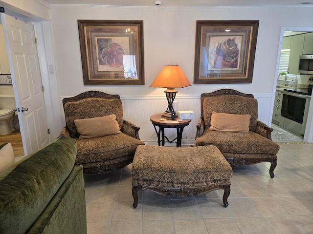 living area with a wainscoted wall, visible vents, and tile patterned floors