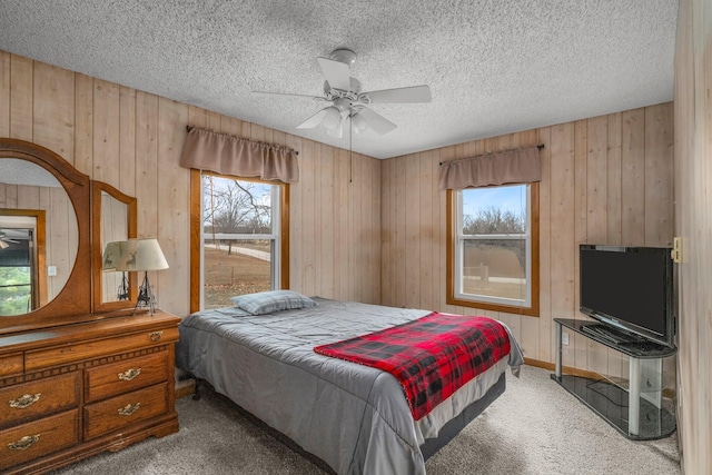 carpeted bedroom with a textured ceiling, ceiling fan, and wooden walls