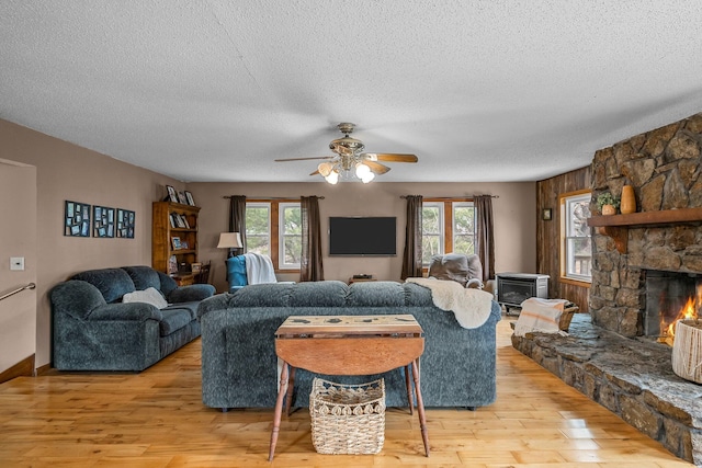 living area with light wood-type flooring, a healthy amount of sunlight, and a stone fireplace