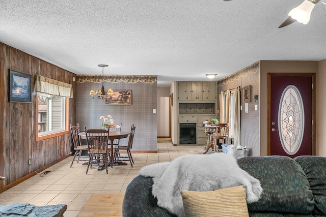 dining area featuring visible vents, baseboards, light tile patterned flooring, a textured ceiling, and ceiling fan with notable chandelier