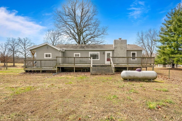 back of property featuring a deck, a yard, and a chimney