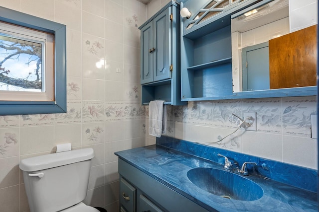 bathroom with toilet, vanity, and tile walls