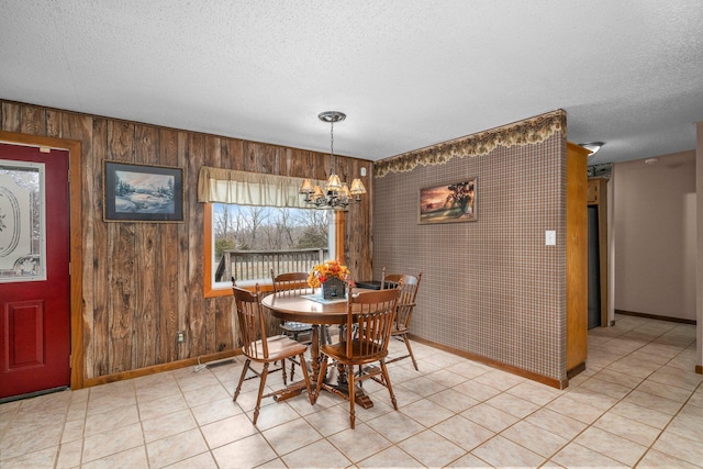 dining area with a chandelier, light tile patterned floors, a textured ceiling, and baseboards