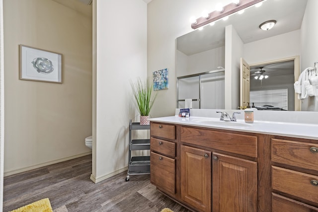 full bathroom with baseboards, toilet, a shower with door, wood finished floors, and vanity