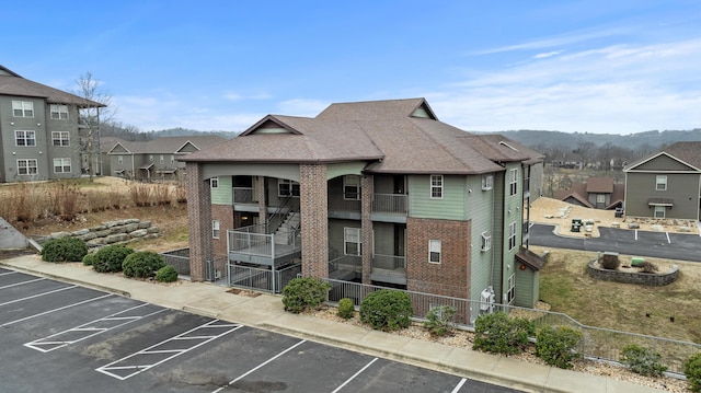 view of property with uncovered parking, fence private yard, and stairway