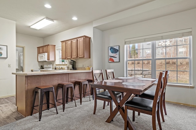 dining space featuring baseboards, light colored carpet, and recessed lighting