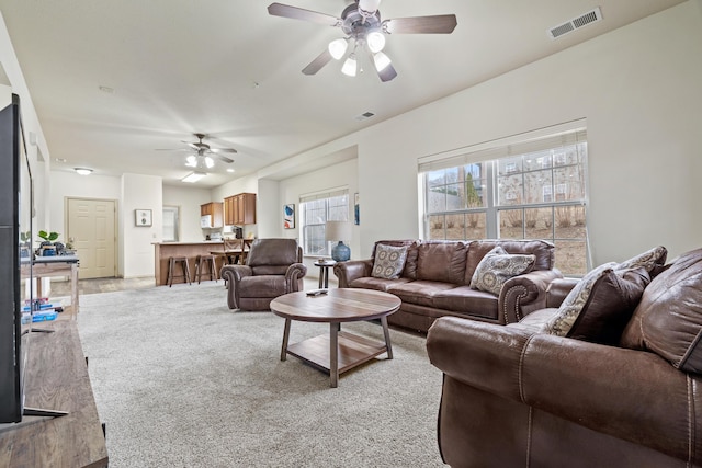 living area with light carpet, visible vents, and a ceiling fan