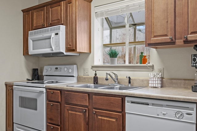 kitchen featuring white appliances, light countertops, and a sink