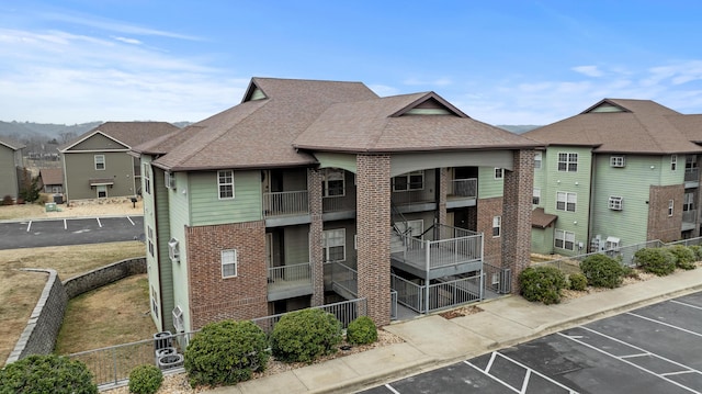 view of building exterior with uncovered parking and fence