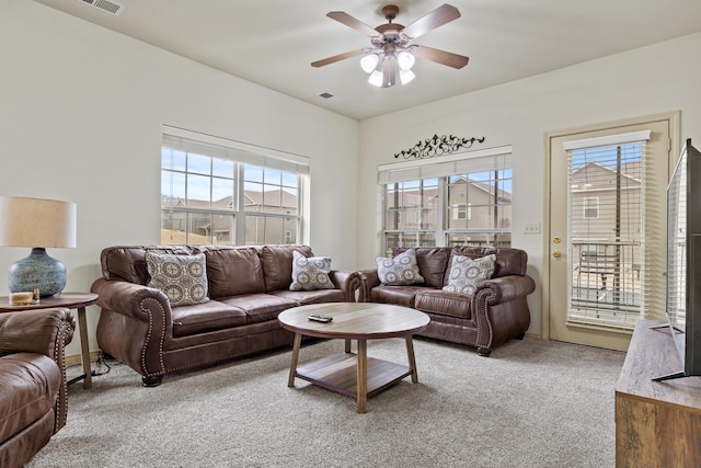 living area with a ceiling fan, light colored carpet, and visible vents