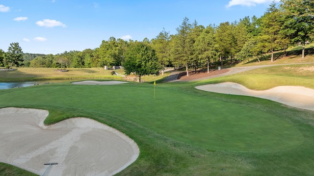 view of property's community featuring view of golf course, a lawn, and a water view