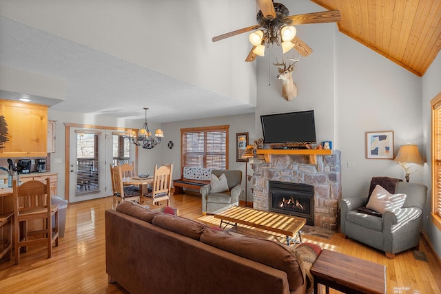 living room featuring ceiling fan with notable chandelier, high vaulted ceiling, light wood-type flooring, and a fireplace