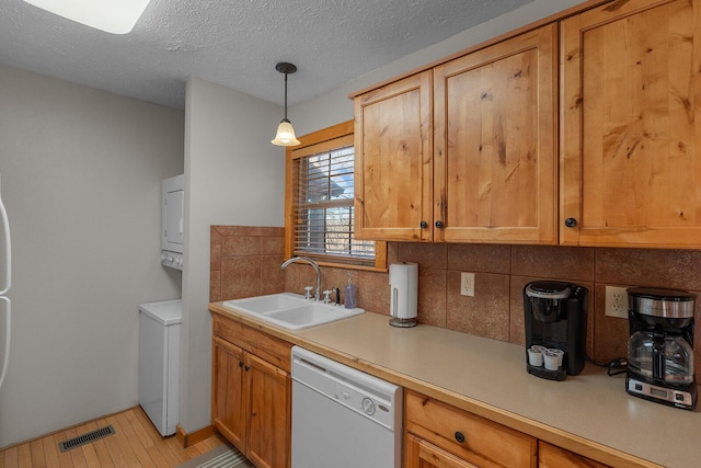 kitchen featuring light countertops, visible vents, backsplash, white dishwasher, and a sink