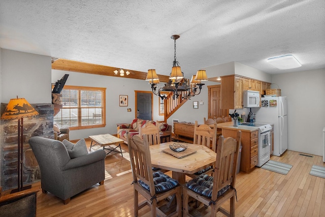 dining space featuring a notable chandelier, a textured ceiling, and light wood finished floors