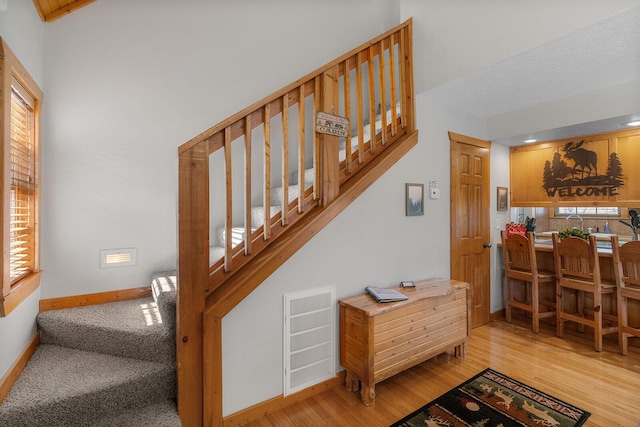 staircase with visible vents, plenty of natural light, baseboards, and wood finished floors