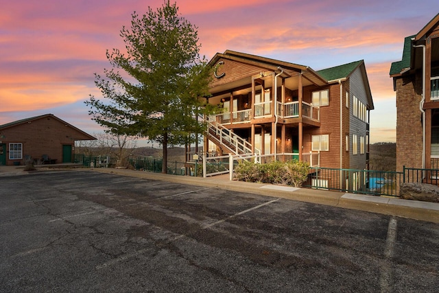 property at dusk with uncovered parking, stairway, and fence