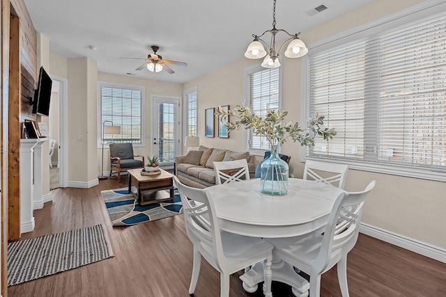 dining room featuring baseboards, visible vents, wood finished floors, and ceiling fan with notable chandelier