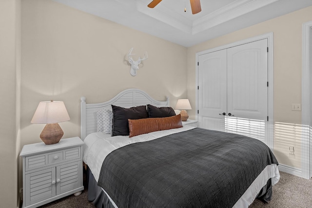 bedroom featuring a raised ceiling, ceiling fan, carpet, crown molding, and a closet