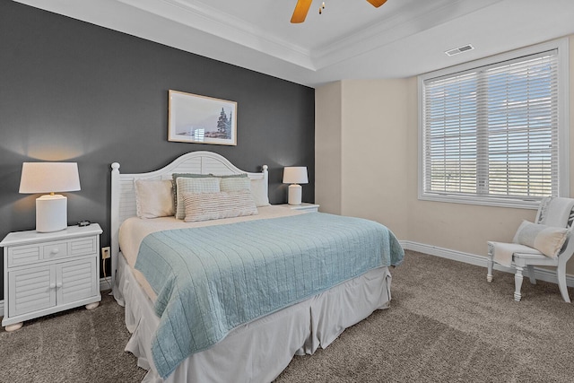 carpeted bedroom featuring a ceiling fan, visible vents, baseboards, ornamental molding, and a tray ceiling