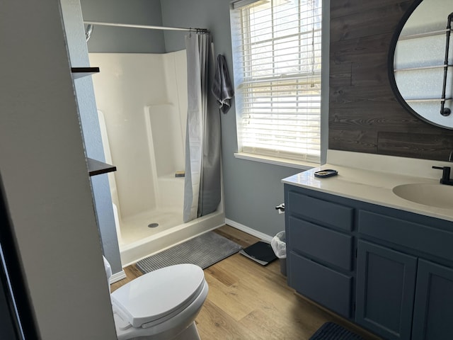 full bathroom featuring toilet, vanity, a shower stall, wood finished floors, and baseboards