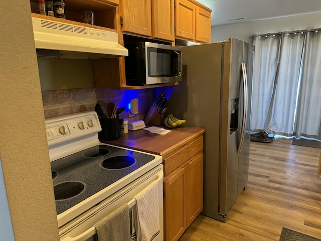 kitchen with light wood finished floors, white range with electric cooktop, stainless steel microwave, brown cabinetry, and under cabinet range hood