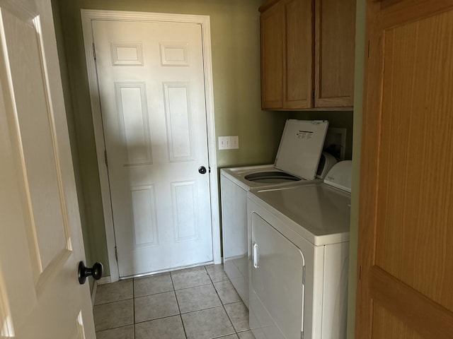 laundry room featuring cabinet space, light tile patterned floors, and washing machine and clothes dryer