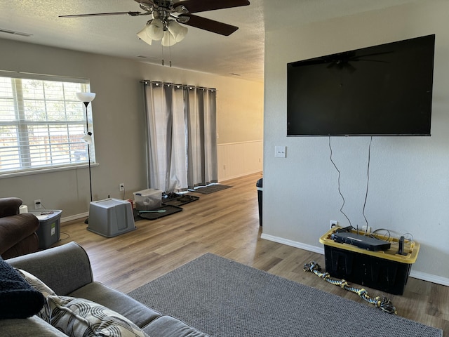 living area with ceiling fan, wood finished floors, and visible vents