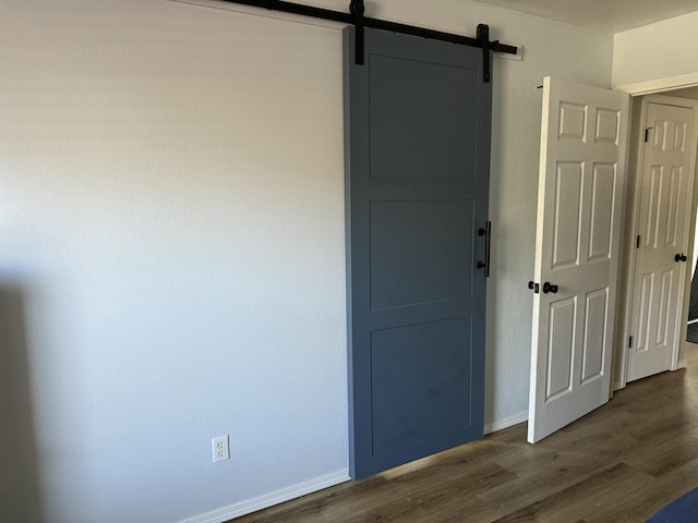 spare room with a barn door, baseboards, and dark wood finished floors