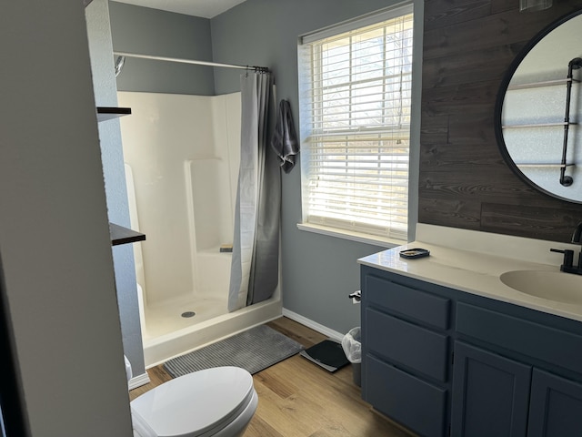 bathroom featuring a stall shower, plenty of natural light, toilet, and wood finished floors