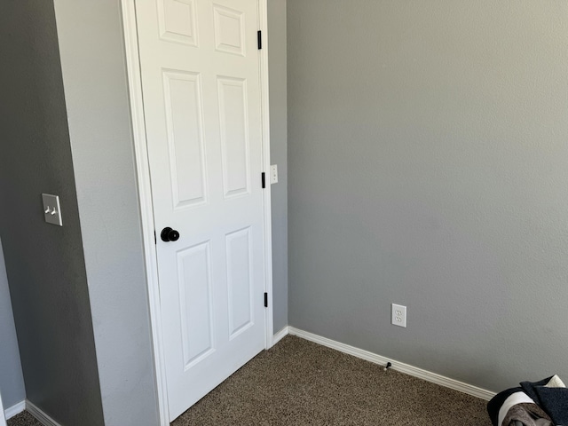 interior space with dark colored carpet and baseboards