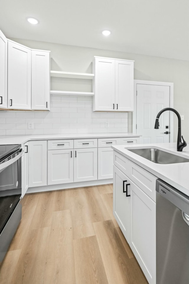 kitchen with a sink, open shelves, stainless steel appliances, white cabinets, and light wood finished floors