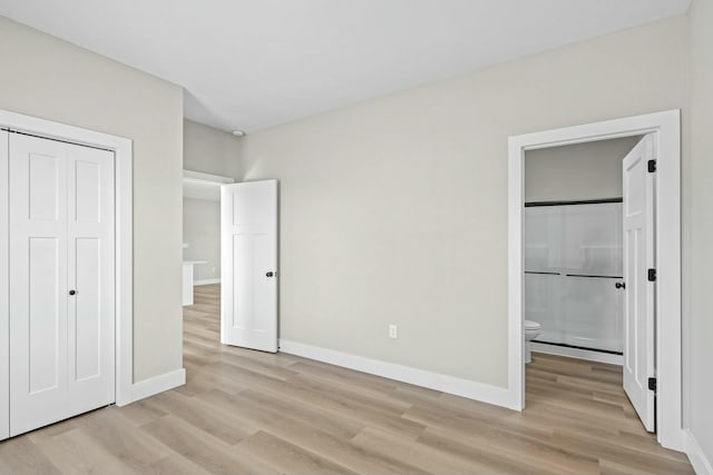 unfurnished bedroom featuring a closet, baseboards, light wood finished floors, and connected bathroom