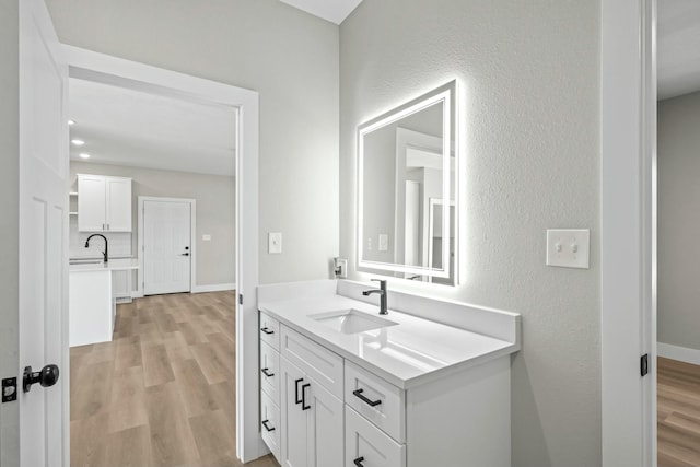 bathroom featuring vanity, wood finished floors, and baseboards