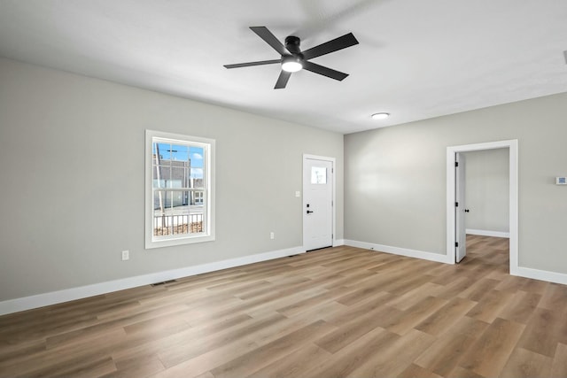 unfurnished room with light wood finished floors, visible vents, a ceiling fan, and baseboards