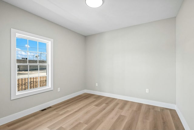 empty room with visible vents, baseboards, and wood finished floors