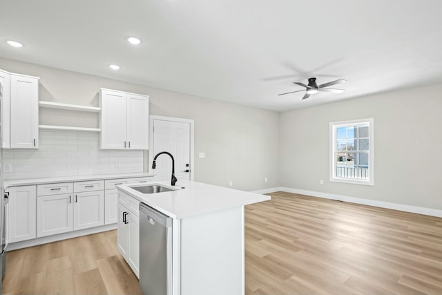 kitchen featuring light wood finished floors, a sink, light countertops, stainless steel dishwasher, and tasteful backsplash